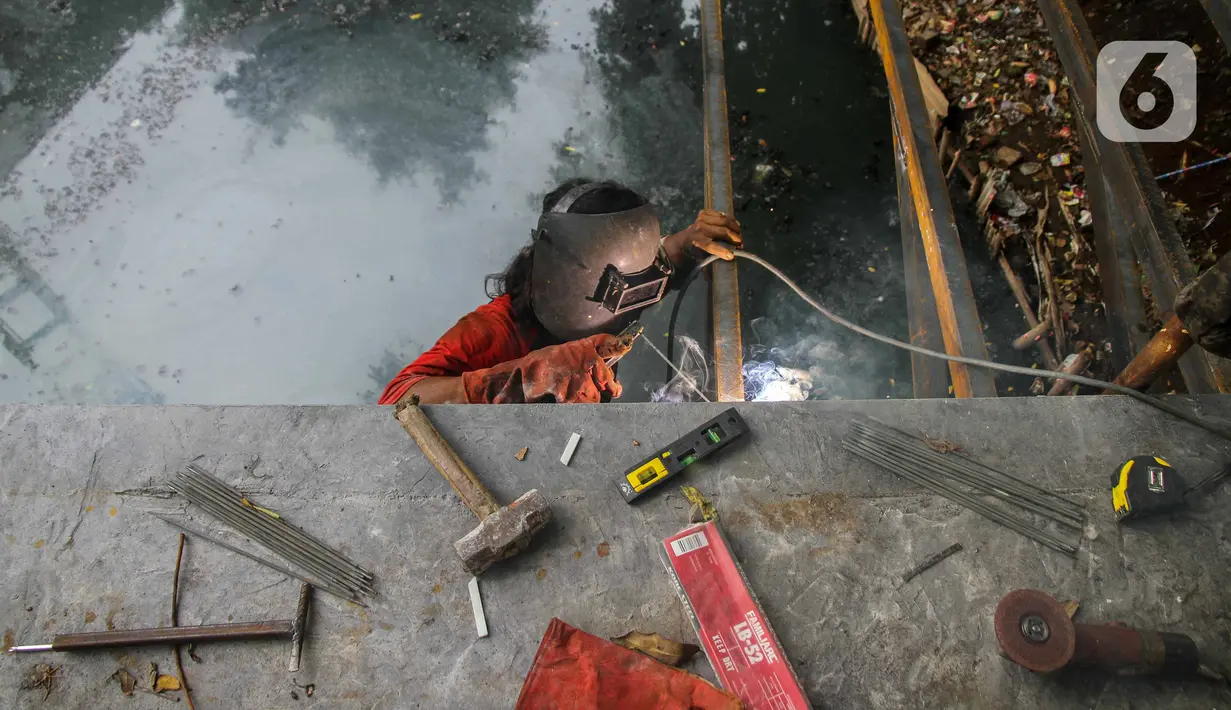 Pekerja menyelesaikan proyek pembangunan jembatan penghubung antarkampung di kawasan Pondok Pinang, Jakarta, Jumat (13/12/2019).  Jembatan yang menghubungkan permukiman di daerah Pondok Pinang dengan kawasan Bintaro tersebut ditargetkan rampung pada akhir Desember. (Liputan6.com/Faizal Fanani)