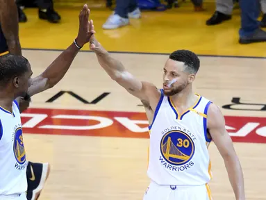 Pemain Golden State Warriors Kevin Durant (35) dan Stephen Curry (30) melakukan selebrasi saat bertanding melawan Cleveland Cavaliers di gim pertama Final NBA 2017 di Oracle Arena di Oakland, California (1/6). (Thearon W. Henderson/Getty Images/AFP)
