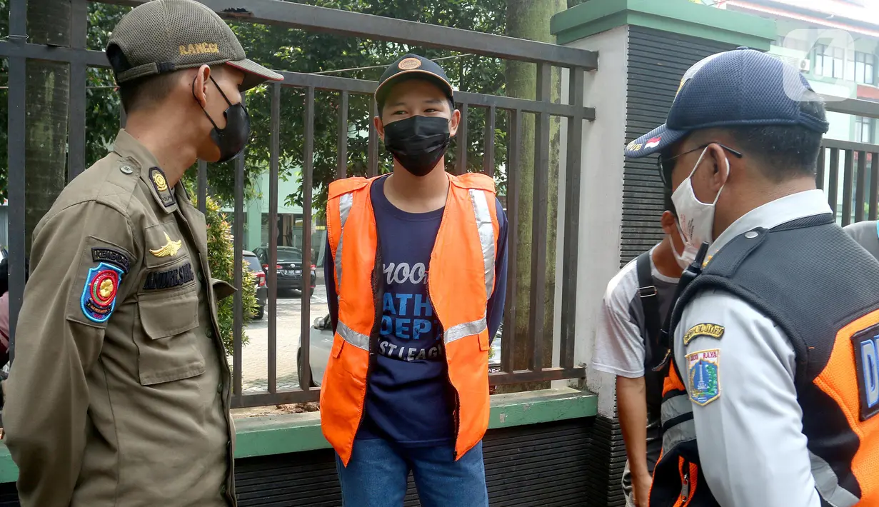 Petugas Satpol PP dan Dishub berbicara dengan warga yang terjaring operasi tertib masker dalam rangka penerapan protokol kesehatan COVID-19 di Jalan Fatmawati, Jakarta, Kamis (10/3/2022). (merdeka.com/Arie Basuki)