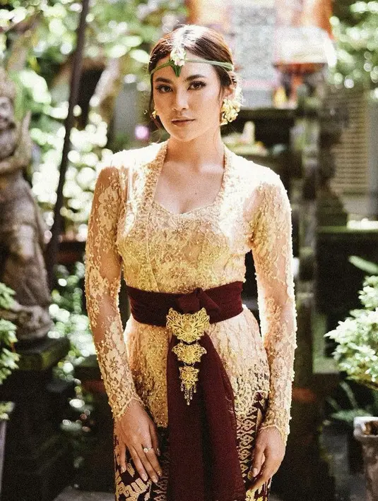 Jebolan ajang pencarian bakat Indonesia Idol ke-10 ini tampil denhan kebaya brokat warna gold dengan obi maroon yang dipercantikan dengan bros khas Bali. Untuk bawahan ia mengenakan kain lulit corak Bali. Penampilannya dilengkapi aksesori seperti anting dan cincin. (@mahaliniraharja)