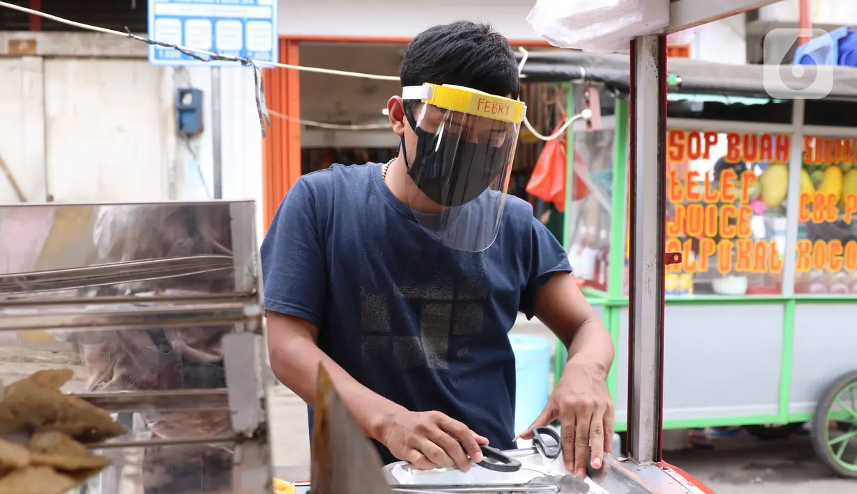 Pedagang mengenakan face sheild atau pelindung wajah saat berjualan di Tangerang, Banten, Rabu (13/5/2020). Penggunaan pelindung wajah tersebut dilakukan untuk mencegah risiko penularan virus corona COVID-19 pada saat berdagang. (Liputan6.com/Angga Yuniar)