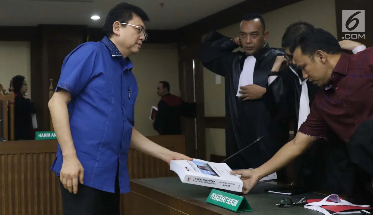 Terdakwa dugaan merintangi proses penyidikan KPK, Lucas (kiri) menyerahkan surat tuntutan kepada tim penasehat hukumnya usai mengikuti sidang di Pengadilan Tipikor, Jakarta, Rabu (6/3). Lucas dituntut 12 tahun penjara. (Liputan6.com/Helmi Fithriansyah)