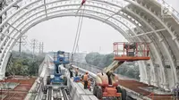 Pekerja menyelesaikan proyek pembangunan Light Rail Transit (LRT) Jabodebek di Stasiun LRT TMII, Jakarta, Senin (14/1). Stasiun LRT TMII dibangun dua lantai yang terdiri dari komersial dan pembelian tiket. (Liputan6.com/Faizal Fanani)