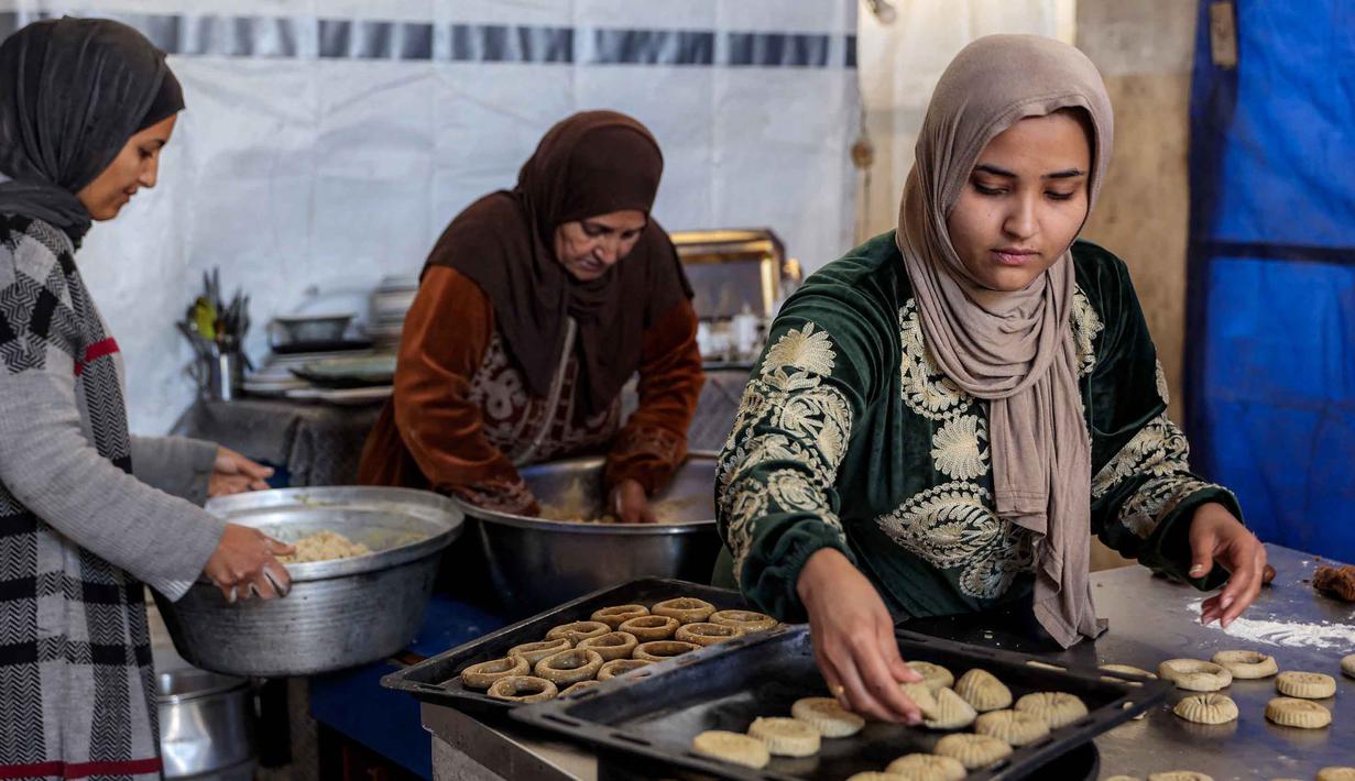 Kaak terbuat dari tepung terigu, minyak zaitun Palestina yang melimpah, dan rempah-rempah aromatik. Tampak dalam foto, para wanita menyiapkan biskuit tradisional "kaak" yang berbentuk cincin menjelang Idul Fitri, hari raya yang menandai berakhirnya bulan puasa suci Ramadan, di Kota Gaza pada 16 Maret 2026. (Omar AL-QATTAA/AFP)