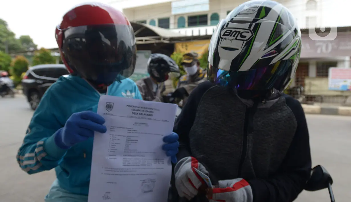Pengendara motor menunjukkan Surat Izin Keluar Masuk (SIKM) saat diperiksa petugas di pos chek point,  Kalimalang Lampiri, Jakarta, Rabu (27/5/2020). (merdeka.com/Imam Buhori)