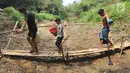 Warga Kampung Gamblok melewati jembatan bambu usai mengambil sisa air Kali Cihoe, Desa Ridomanah, Bekasi, Jawa Barat, Kamis (15/8/2019). Bantuan air bersih dirasa kurang bagi warga sebab distribusi tidak merata dan dilakukan hanya pada awal-awal pemberitaan media massa. (merdeka.com/Arie Basuki)