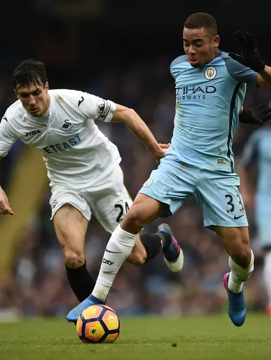 Gabriel Jesus (kanan) berusaha membawa bola dari kejaran gelandang Swansea City, Jack Cork pada lanjutan liga Inggris di Stadion Etihad, Manchester (6/2). City menang atas Swansea dengan skor 2-1.  (AFP Photo / Oli ScArff)