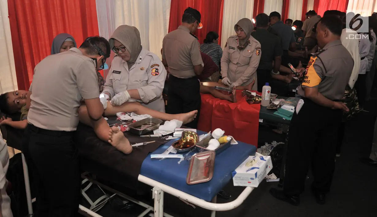 Petugas medis menangani anak-anak  saat sunatan massal gratis dalam acara Bakti Sosial dan Kesehatan Polri di Mapolsek Ciracas, Jakarta, Kamis (4/7/2019). Bakti Sosial dan Kesehatan yang digelar dalam rangka memperingati HUT ke-73 Bhayangkara. (merdeka.com/Iqbal Nugroho)