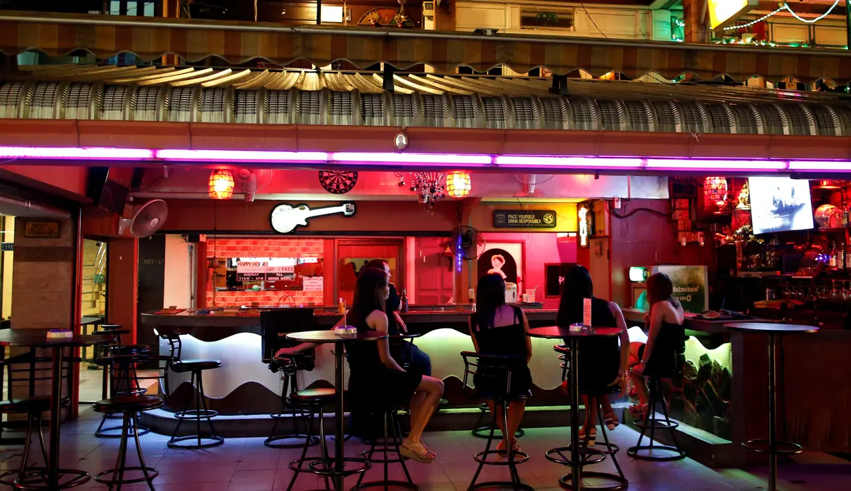 Para wanita berpakaian hitam duduk di dalam sebuah bar di distrik hiburan malam, setelah beredar kabar meninggalnya Raja Bhumibol Adulyadej di Bangkok, Thailand, (17/10). (REUTERS/Issei Kato)