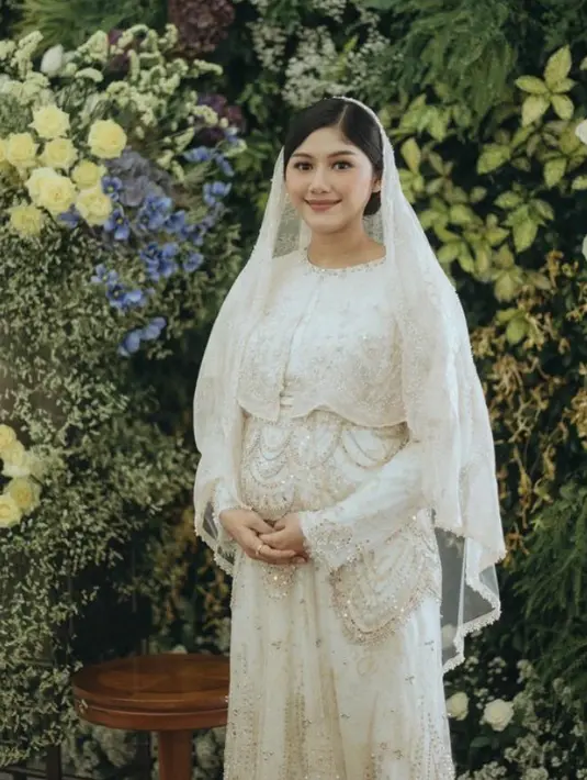 Dress memiliki aksen layerin di bagian atas dipadukan dengan kerudung lace di atas rambut yang disanggul updo. Dengan riasan wajah warmnya.  [@erinagudono]