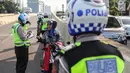 Petugas kepolisian memberikan surat tilang kepada pengendara sepeda motor  yang melintasi JLNT Kampung Melayu-Tanah Abang, Jakarta, Selasa (25/7). Sepeda motor dilarang melintas di JLNT tersebut karena merupakan jalur cepat. (Liputan6.com/Faizal Fanani)
