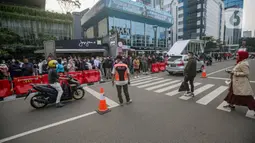 Personel gabungan dari unsur polisi hingga Satpol PP mengatur lalu lintas di kawasan zebra cross Dukuh Atas, Jakarta, Rabu (27/7/2022). Mereka dikerahkan untuk memantau kegiatan peragaan busana Citayam Fashion Week (CFW) guna meminimalisir terjadinya kriminalitas, kemacetan, hingga parkir liar. (Liputan6.com/Faizal Fanani)