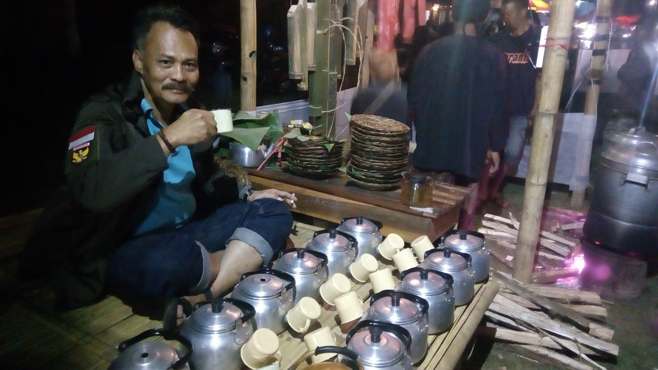 Salah satu pengunjung tengah menikmati hidangan teh hangat dalam festival Nyaneut di Garut