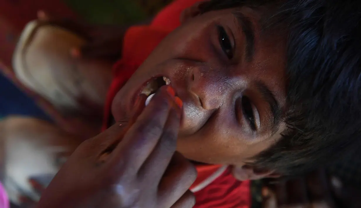 Seorang anak diberi vaksin kolera oleh sukarelawan Bangladesh di kamp pengungsi Thankhali di distrik Ukhia (10/10). Di tengah kekhawatiran wabah, PBB memberikan vaksinasi kolera untuk hampir satu juta orang Rohingya. (AFP Photo/Indranil Mukherjee)