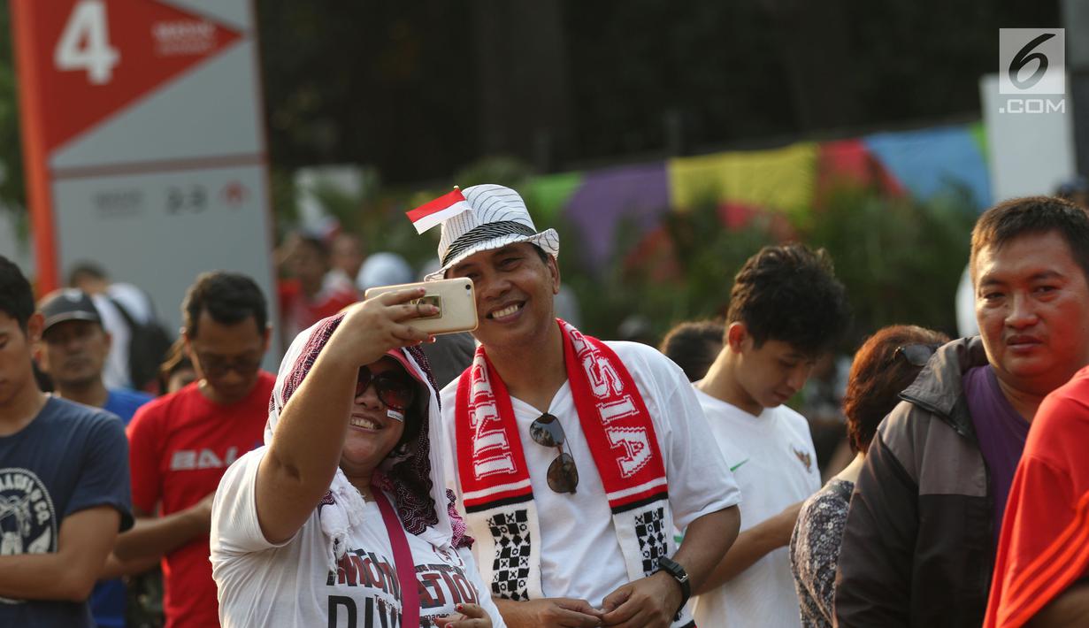 Calon penonton berswafoto sambil antre untuk mendapatkan tiket final bulu tangkis beregu putra di sekitar tiket boks di kawasan GBK, Jakarta, Rabu (22/8). Final bulu tangkis beregu putra mempertemukan Indonesia vs China. (Liputan6.com/Helmi Fithriansyah)