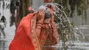 Seorang pemuja Hindu melakukan ritual mandi suci di kolam sekitar monumen India Gate dalam ritual pemujaan dewa matahari selama Festival Chhath Puja di New Delhi, Selasa (13/11). (Sajjad HUSSAIN / AFP)