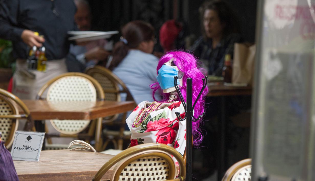 Pemandangan yang disebut Calaca (sosok tengkorak atau kerangka), yang biasa digunakan untuk dekorasi selama Day of the Death, di sebuah restoran di Coyoacan, Mexico City, Selasa (20/10/2020). Restoran tersebut menggunakan tengkorak untuk menjaga jarak di tengah pandemi COVID-19. (CLAUDIO CRUZ/AFP)