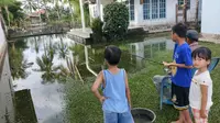 Warga Jalan Yayasan 2 bisa memancing di depan rumahnya seusai hujan mengguyur Kota Palembang dengan derasnya (Liputan6.com / Nefri Inge)
