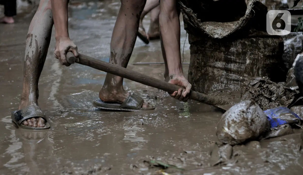 Warga membersihkan lumpur di sekitar rumah usai banjir menerjang Perumahan Pondok Gede Permai, Jatiasih, Bekasi, Jawa Barat, Kamis (2/1/2020). Terjangan banjir setinggi lima meter tersebut menyisakan lumpur dan sampah yang memenuhi seluruh kompleks perumahan. (merdeka.com/Iqbal Nugroho)