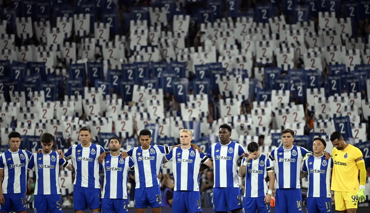 Sejumlah pemain FC Porto mengheningkan cipta dengan latar belakang para penonton yang sedang memegang plakat bergambar nomor punggung dua untuk mengenang kepergian Diogo Costa sebelum laga Liga Portugal 2025/2026 melawan Vitoria Guimaraes SC di Estadio Do Dragao, Porto, Portugal, Senin (11/08/2025) waktu setempat. (AFP/Miguel Riopa)