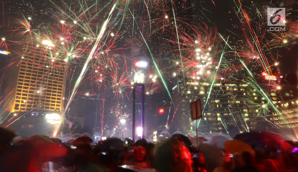 Kembang api menghiasi malam pergantian tahun baru 2019 di kawasan Bundaran HI, Jakarta, Selasa (1/1). Hujan yang mengguyur Jakarta tidak menyurutkan warga menikmati kembang api tahun baru. (Liputan6.com/Angga Yuniar)