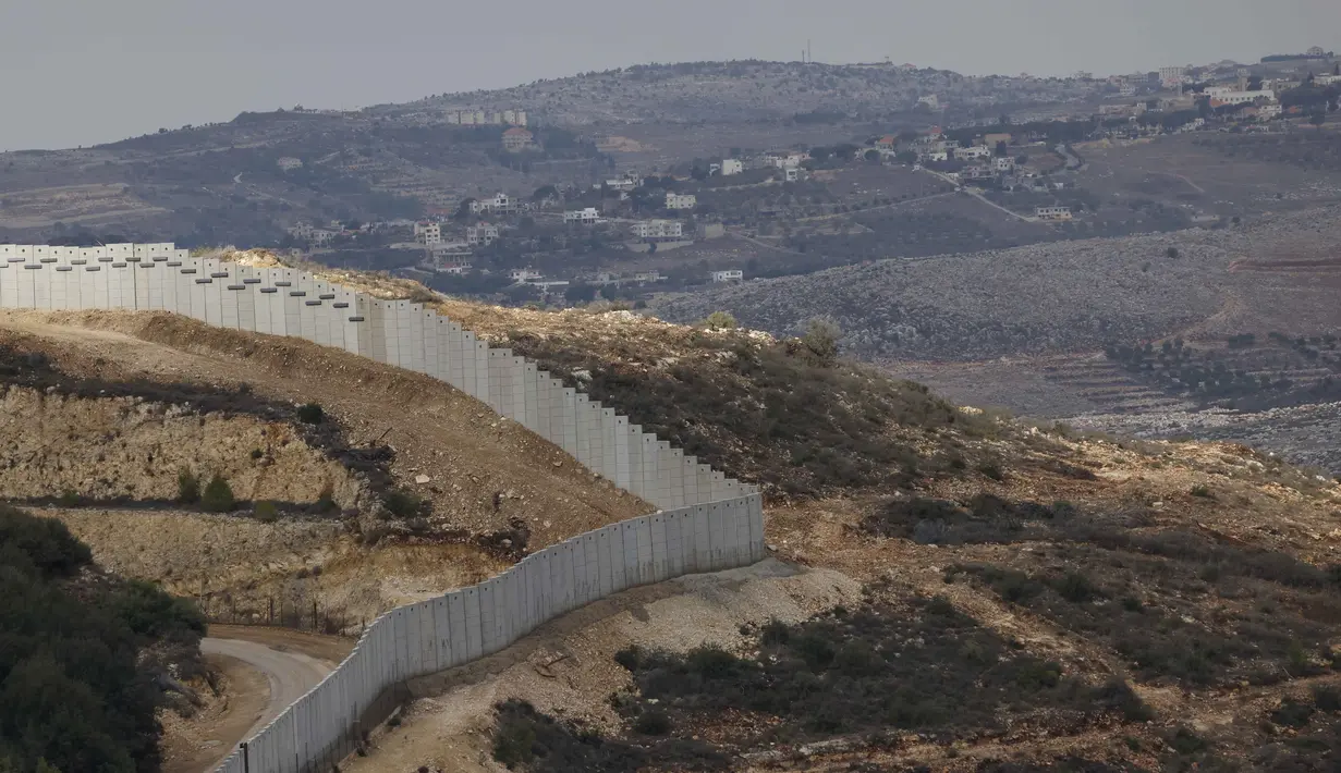 Sebuah foto yang diambil dari Israel memperlihatkan perbatasan yang memisahkan Israel utara dari Lebanon selatan, dengan desa Lebanon Ain Ebel terlihat di latar belakang pada 16 November 2025. Israel membangun tembok perbatasan baru di sepanjang garis perbatasan dengan Lebanon wilayah bagian Selatan. (Jalaa MAREY/AFP)