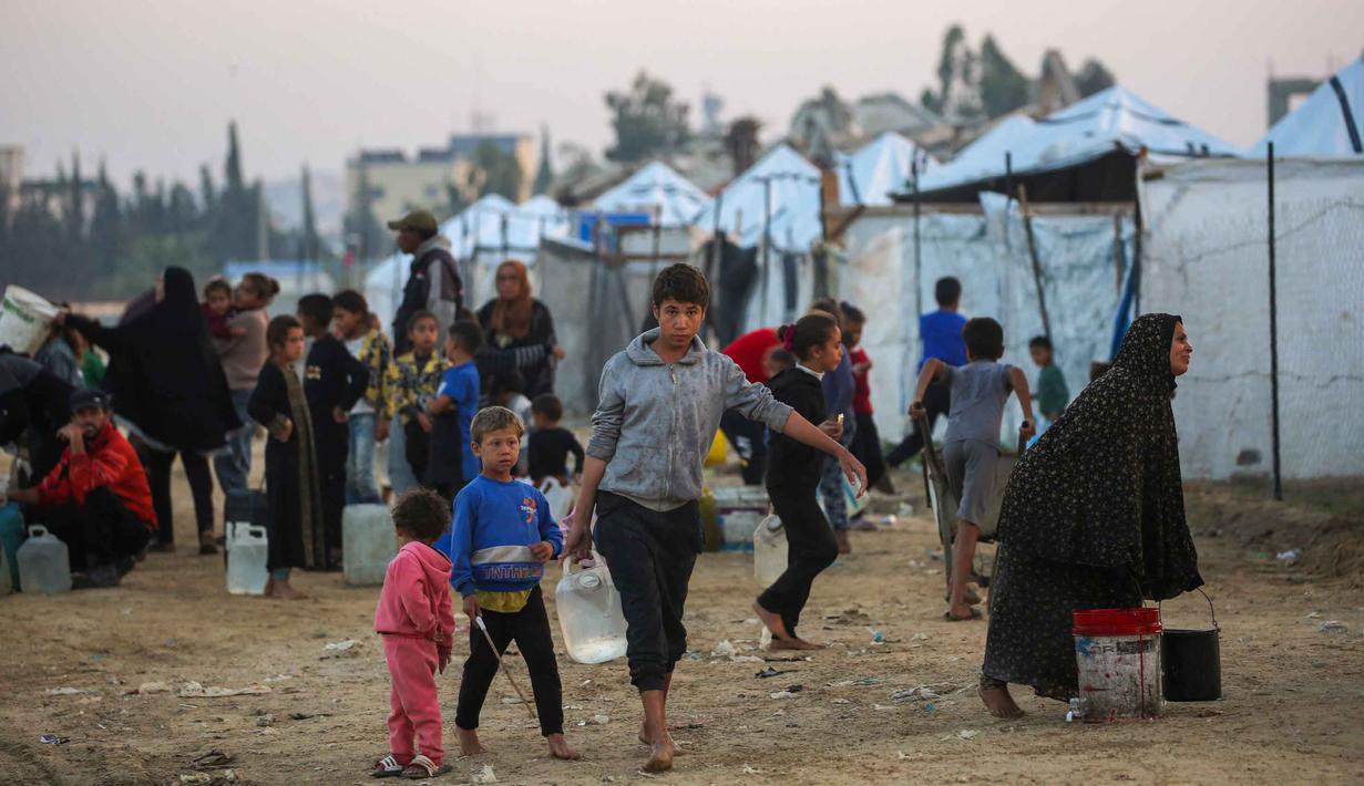 Orang-orang mengisi wadah air mereka di kamp Nuseirat untuk pengungsi Palestina di Jalur Gaza tengah pada Kamis 4 Desember 2025. Hingga saat ini, akses bantuan air bersih di kamp pengungsi Nuseirat di Jalur Gaza tengah masih sangat terbatas. (Eyad Baba/AFP)