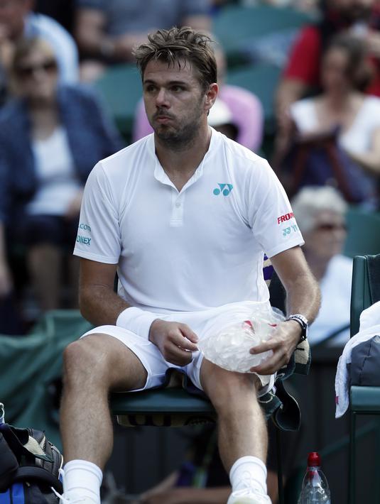 Stan Wawrinka mendinginkan lutut kaki dengan es saat melawan etenis Rusia, Daniil Medvedev di  Wimbledon Tennis Championships 2017, London, (3/7/2017). Stan kalah 4-6, 6-3, 4-6, 1-6. (AP/Kirsty Wigglesworth)