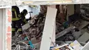 Pemadam kebakaran mencari korban di reruntuhan rumah susun yang roboh akibat ledakan di Milan, Italia, Minggu (12/6) waktu setempat. Sedikitnya tiga orang tewas akibat ledakan yang berasal dari lantai tiga bangunan tersebut. (REUTERS/Flavio Lo Scalzo)