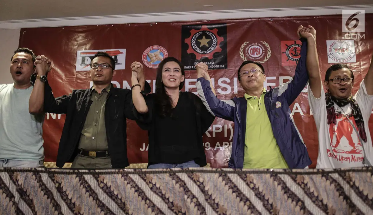 Ketum Konfederasi Pekerja RI, Rieke Diah Pitaloka bersama federasi buruh mengangkat tangan ke atas usai konferensi pers Hari Buruh di Jakarta, Minggu (29/4). Rieke juga menyampaikan 5 maklumat untuk Presiden Joko Widodo. (Liputan6.com/Faizal Fanani)