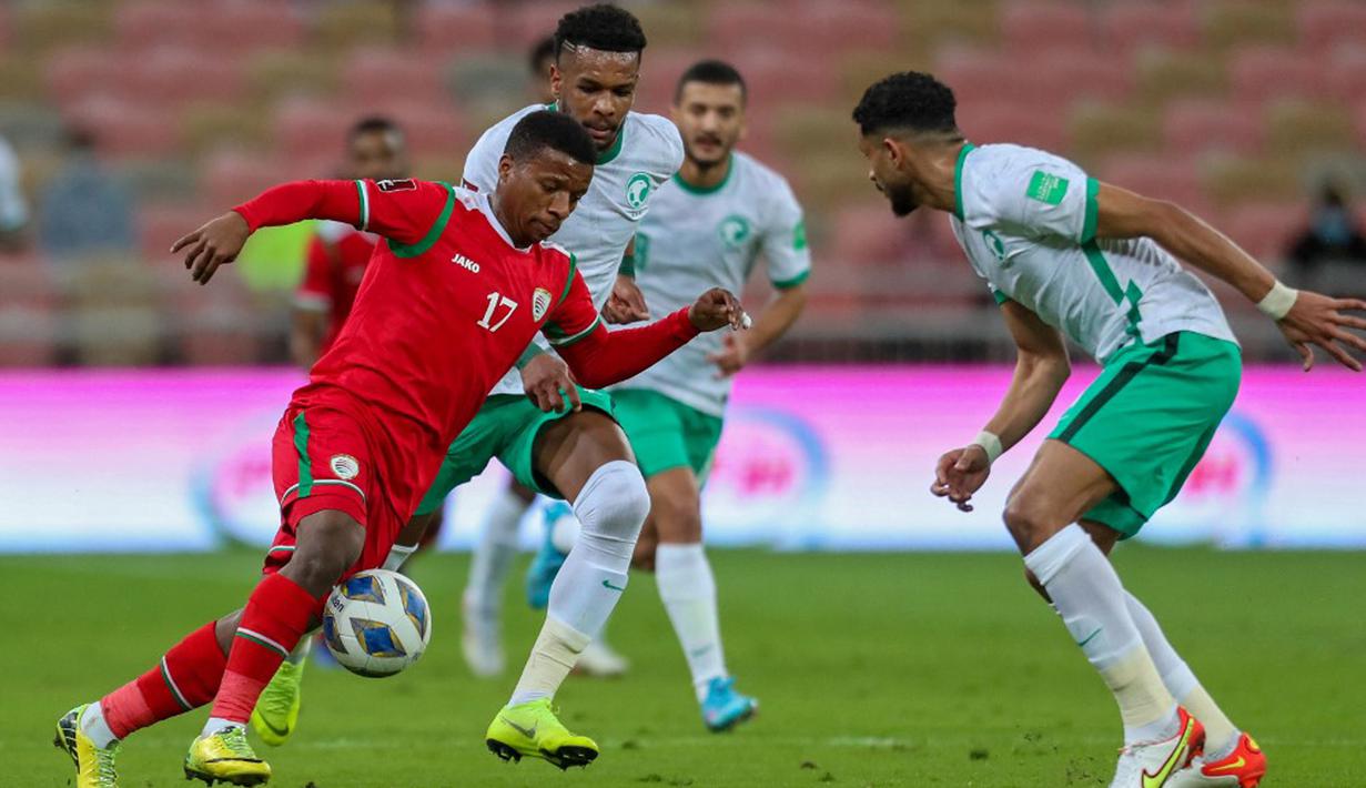 Pemain Oman Arshad al-Alawi (kiri) dibayangi pemain Arab Saudi Ali al-Bulaihi (tengah) pada pertandingan sepak bola Kualifikasi Piala Dunia 2022 di Stadion King Abdullah Sport City, Jeddah, Arab Saudi, 27 Januari 2022. Arab Saudi menang 1-0. (AFP)