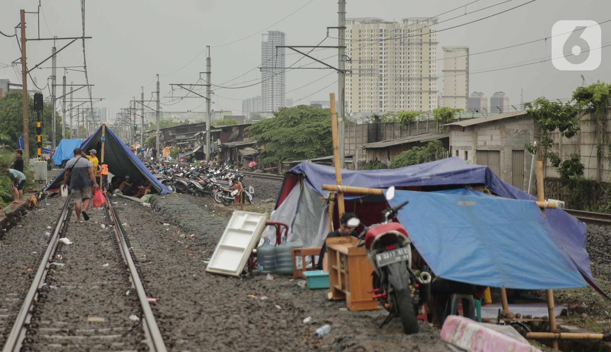 Pengungsi banjir mendirikan tenda di jalur rel kereta commuterline Tangerang-Duri di Kembangan Baru, Jakarta, Jumat (3/1/2020). Jalur rel yang nonaktif sementara karena banjir dimanfaatkan warga sekitar untuk mendirikan tenda darurat karena rumah mereka masih terendam. (Liputan6.com/Faizal Fanani)