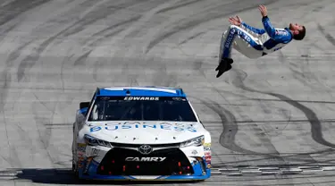 Pembalap Carl Edwards melakukan aksi gila dengan salto dari mobil ketika mesin dalam keadaan berjalan perlahan usai merayakan kemenangan NASCAR Sprint Cup Series Food City 500 di Bristol Motor Speedway (17/4). (AFP/Matt Sullivan)