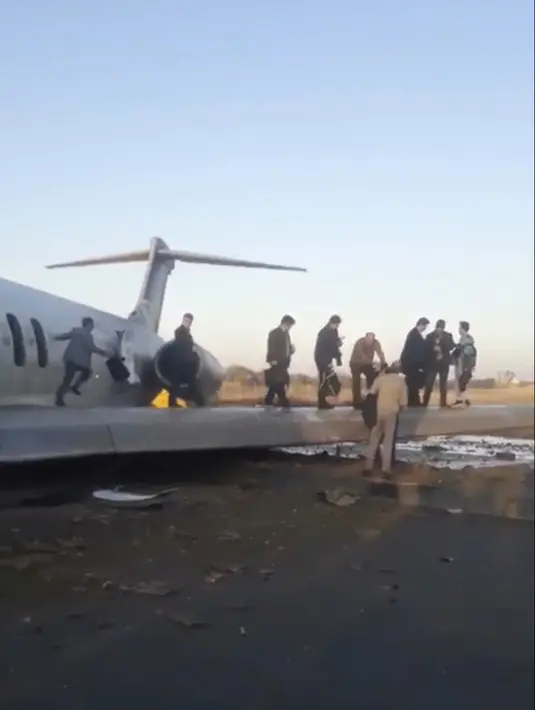 Penumpang berjalan di atas sayap pesawat Caspian usai tergelincir di jalan raya di Kota Bandar-e Mahshahr, Iran (27/1/2020). Maskapai Caspian Airlines yang membawa sekitar 150 penumpang dan kru pesawat tersebut terbang dari Bandara Mehrabad, Teheran. (Iran's Civil Aviation Network News via AP)