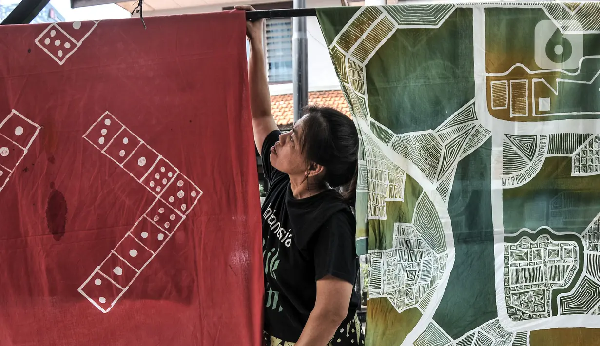 Pengajar menjemur batik hasil pelatihan di Rumah Batik Palbatu, Jakarta, Minggu (2/10/2022). Dalam rangka memeriahkan Hari Batik Nasional, Rumah Batik Palbatu menggelar pelatihan membatik kepada masyarakat umum sebagai upaya meningkatkan minat terutama bagi generasi milenial dalam melestarikan seni kriya tersebut. (merdeka.com/Iqbal S. Nugroho)