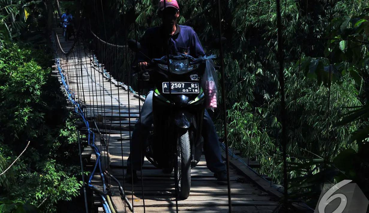 Seorang pengendara motor nekat melintas di atas jembatan gantung Lebak yang kondisinya sudah memprihatinkan. Foto diambil pada Selasa (5/11/2014) (Liputan6.com/Johan Tallo)