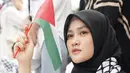 Hadiri aksi bela Palestina, Henny Rahman datang bersama Alvin Faiz. Henny Rahman tampil sederhana dengan jilbab hitam, syal Palestina dan makeup yang sangat natural. Artis berusia 29 tahun ini tak lupa memakai atribut dan bawa bendera Palestina. Dalam keterangan unggahannya, Henny berharap aksi tersebut bisa membuka mata dunia dan berharap Palestina segera merdeka. (Liputan6.com/IG/@alvin_411)