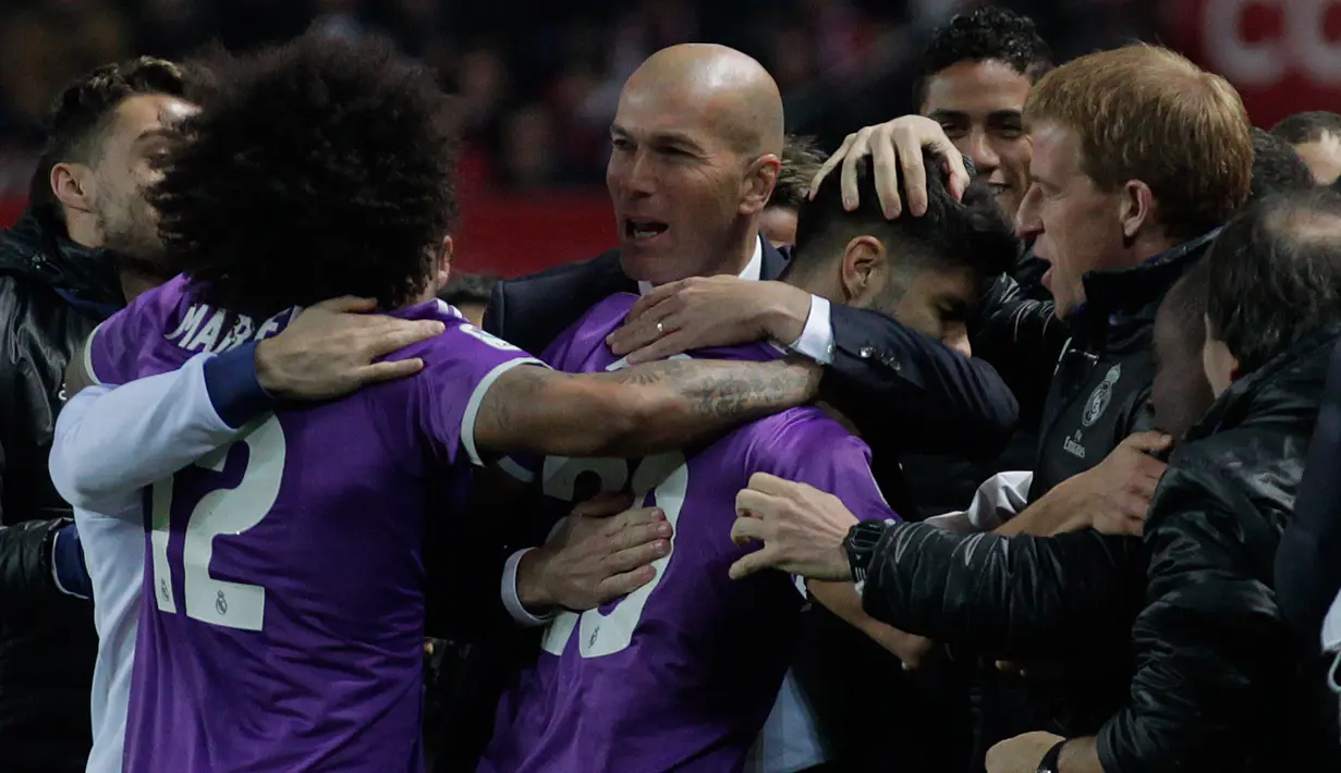Zinedine Zidane berpelukan dengan pemainnya usai memastikan lolos ke perempat final Copa del Rey setelah menang agregat 6-3 atas Sevilla, Spanyol, Kamis (12 /1).  (AP Photo/ Angel Fernandez)