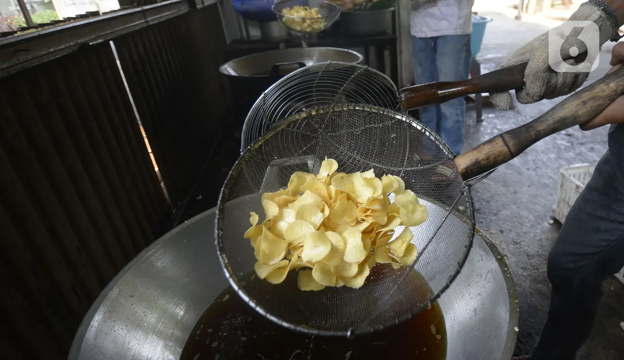 Pekerja mengangkat keripik singkong rumahan usai digoreng di Kampung Kopi, Gunung Sindur, Bogor, Jawa Barat, Selasa (8/9/2020). Camilan yang dijual dengan harga Rp 8 ribu hingga Rp 50 ribu tergantung rasa tersebut banyak diminati warga di masa pandemi. (merdeka.com/Dwi Narwoko)