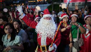 Seorang peserta yang mengenakan kostum Santa Claus menjadi pusat perhatian warga di sela-sela bernyanyi bersama. Tampak dalam foto, seorang pria berpakaian Santa Claus menyanyikan lagu-lagu Natal di Jakarta, Indonesia, Selasa, 23 Desember 2025. (AP Photo/Dita Alangkara)