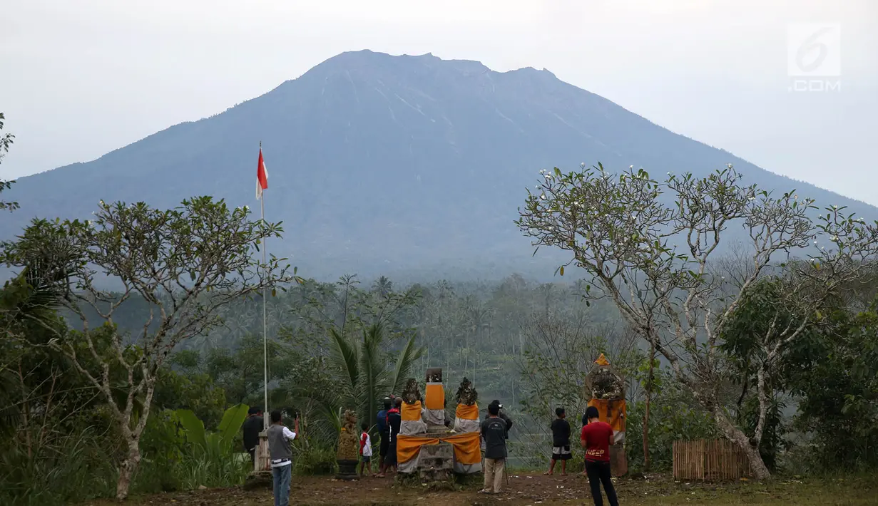 Sejumlah warga mengamati kondisi Gunung Agung, kawasan Karangasem, Bali, Sabtu (2/12). Hingga hari ini, penampakan asap dari kawah Gunung Agung semakin berkurang dibanding beberapa hari lalu. (Liputan6.com/Immanuel Antonius)