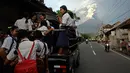 Pelajar bersiap berangkat ke sekolah menggunakan mobil saat erupsi Gunung Agung di Karangasem, Bali, (28/11). Pihak berwenang memberi peringatan kepada warga untuk mengungsi akibat stasus Gunung Agung yang dari siaga ke awas. (AP Photo/Firdia Lisnawati)