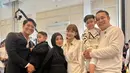 Gilang Dirga hadir dengan sang istri dan putranya. Istrinya tampil feminim dengan atasan kemeja satin putih dipadukan mini skirt sambil membawa tas putih. [@gilangdirga]