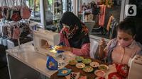 Perajin menyelesaikan pembuatan masker batik di Butik Elemwe, Jakarta, Jumat (2/10/2020). Spesifikasi masker kain ber-SNI terbagi menjadi tiga tipe antara lain tipe A untuk penggunaan umum, tipe B penggunaan filtrasi bakteri, dan tipe C penggunaan filtrasi partikel. (Liputan6.com/Faizal Fanani)
