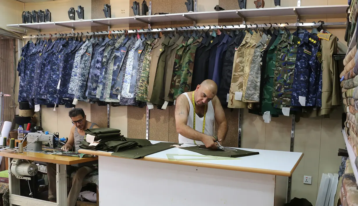 Penjahit Irak menyelesaikan pembuatan seragam militer di Baghdad (13/9). Perang yang berlangsung di Irak membuat para penjahit pakaian biasa kebanjiran orderan membuat seragam militer dan aksesorisnya. (AFP Photo/Sabah Arar)