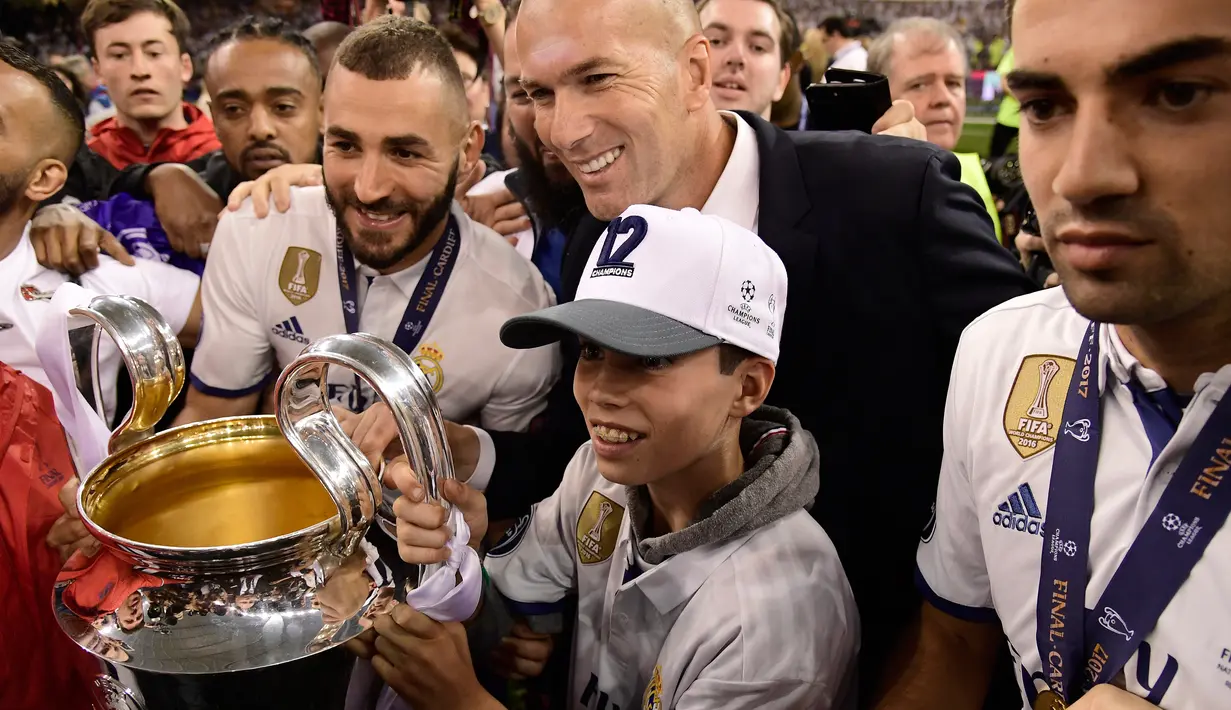 Pelatih Real Madrid Prancis Zinedine Zidane bersama anak-anaknya Elyaz dan Enzo berpose dengan piala usai Real Madrid memenangkan pertandingan Liga Champions di Stadion Cardiff, Wales (3/6). (AFP Photo/Javier Soriano)