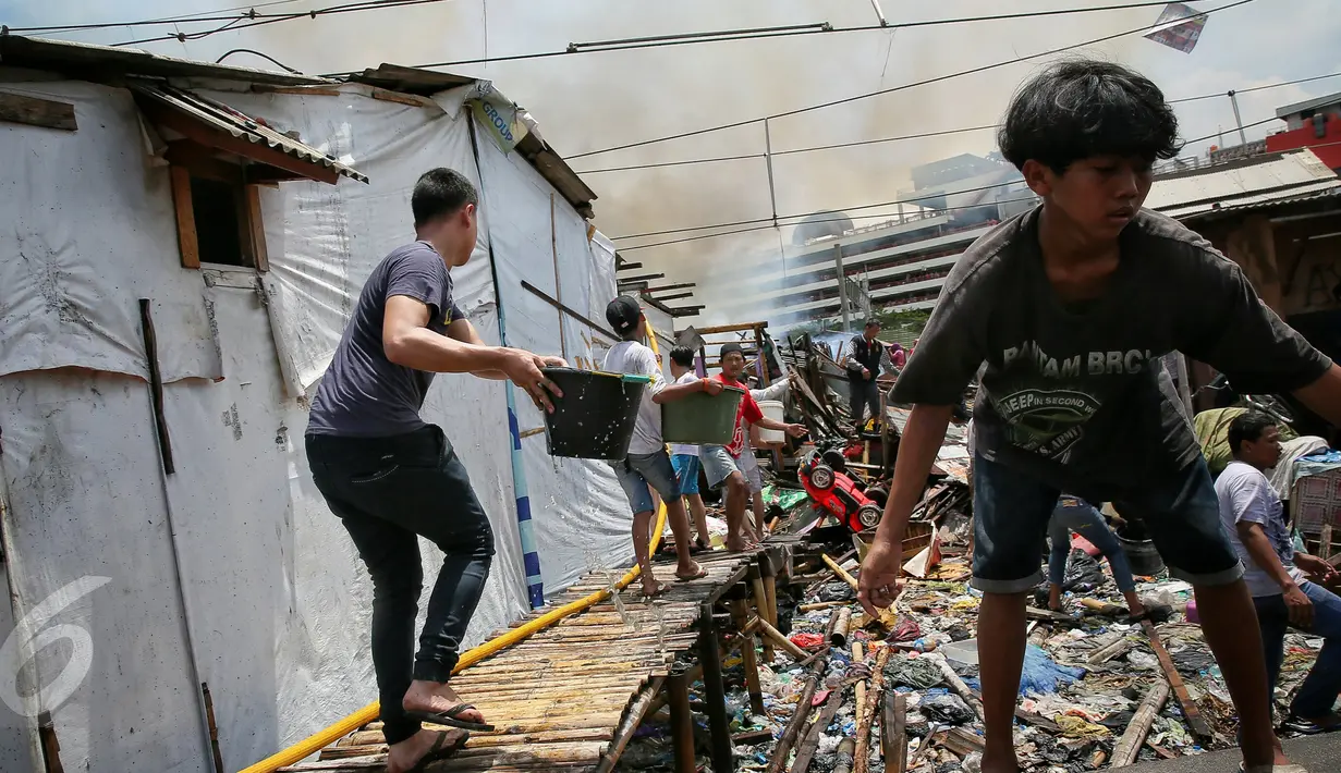 Warga berusaha memadamkan api yang membakar ratusan rumah di Kampung Bandan, Ancol, Jakarta, Selasa (26/1). Lebih dari 27 mobil pemadam dikerahkan untuk menjinakkan api yang membakar bangunan semi permanen itu. (Liputan6.com/Faizal Fanani)