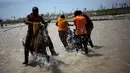 Warga menunggangi kuda saat sejumlah pria membantu rekannya menyeberangi sungai di Les Anglais, 10 Oktober 2016. Selain merusak ribuan rumah, badai Matthew di Haiti juga memutus jembatan yang merupakan akses utama warga. (REUTERS/Andres Martinez Casares)