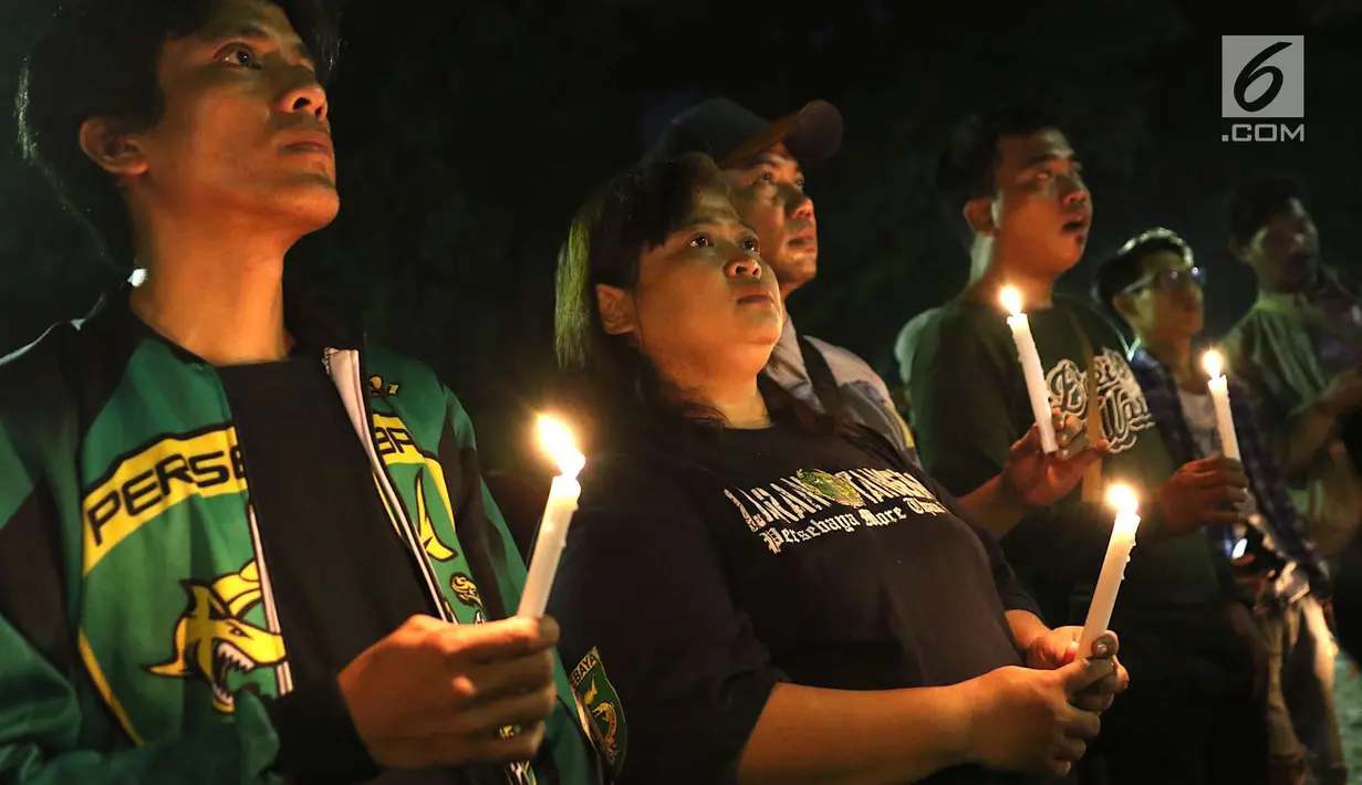 Gabungan suporter klub sepak bola memanjatkan doa sambil menyalakan lilin dalam aksi solidaritas terkait tragedi teror bom di Surabaya dan Sidoarjo di Taman Suropati, Jakarta, Senin (14/5). (Liputan6.com/Immanuel Antonius)