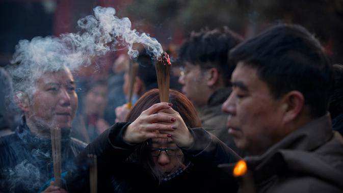 Seorang wanita memegang dupa berdoa di Kuil Lama di Beijing (5/2). Orang-orang China merayakan hari pertama Tahun Baru Imlek pada hari Selasa, Tahun Babi di zodiak Tiongkok dengan berdoa di kuil. (AP Photo/Mark Schiefelbein)